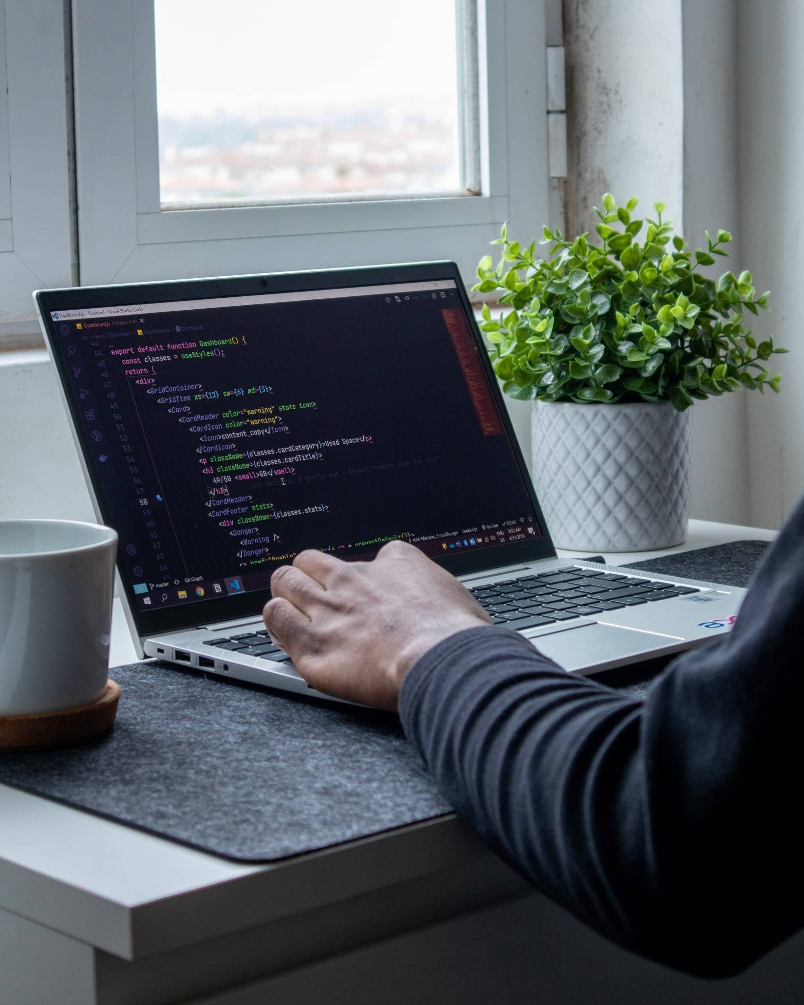 Laptop with code on the screen and a cup of coffee next to it.